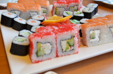 Salmon and caviar rolls served on a plate. sushi or rolls are held with chopsticks. with soy sauce, ginger and wasabi