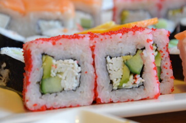 Salmon and caviar rolls served on a plate. sushi or rolls are held with chopsticks. with soy sauce, ginger and wasabi