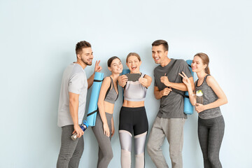 Fototapeta premium Group of people with yoga mats taking selfie near color wall