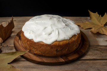 Cake on the bench in autumn with a book and maple falling leaves