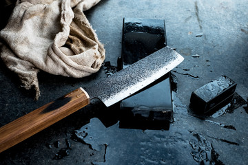 High angle close up of handmade knife on whetstone.