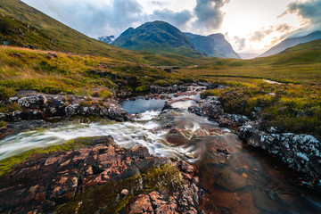 Scotland landscape view with cloudy weather with blurred spring river in the foreground, Long exposure shot