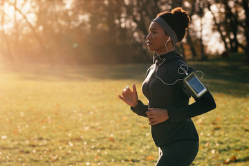 Dedicated African American athlete jogging in nature.
