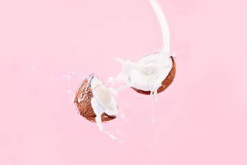 Coconut and spray of coconut milk over pink background, Broken coconut levitation