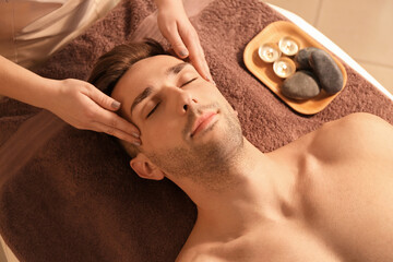 Obraz na płótnie Canvas Handsome young man receiving massage in spa salon