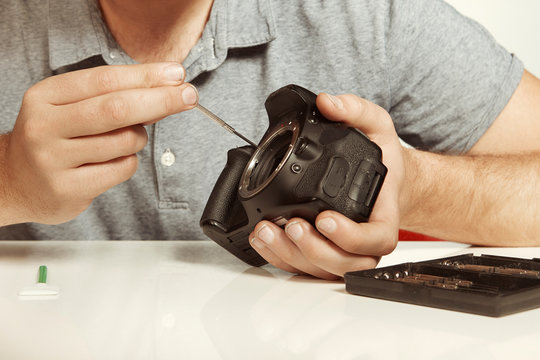 Crazy technician repairing digital camerabody bad way like a doctor