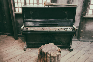 Fototapeta na wymiar Broken piano in an old dirty building. Dusty wooden room with a forgotten musical instrument