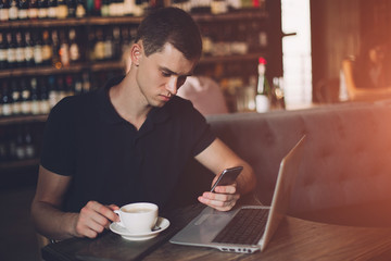 Businessman working on a laptop and using phone in a cafe.
