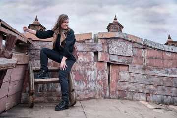 Corsair woman with a knife on board a wooden ship against a gloomy sky on Halloween