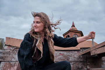 Girl with hair flying in the wind in old clothes and a knife in her hand