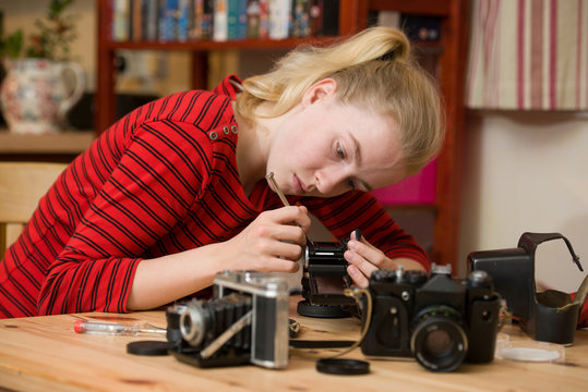 Teenage girl using a small screwdriver to repair an antique film camera
