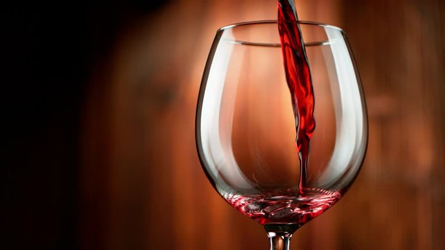 Super slow motion of pouring red wine with wooden background. Filmed on high speed cinema camera, 1000 fps
