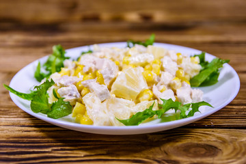 Festive salad with chicken breast, canned pineapple, cheese, sweet corn and mayonnaise on wooden table