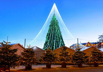 Fototapeta premium Night Cityscape with Christmas Market at Cathedral square in Winter Vilnius, Lithuania. Advent Fair Decoration and Stalls with Crafts Items on the Bazaar. Lithuanian street Xmas and holiday