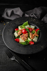 Salad of iceberg lettuce, lettuce, cherry tomatoes, grilled chicken and dorblu cheese. Nutritious, dietary, fitness food. Black boards background