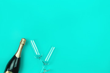 Champagne bottle and two glasses on trendy mint background with place for text. Flat lay style. Holiday concept. Mockup for your design.