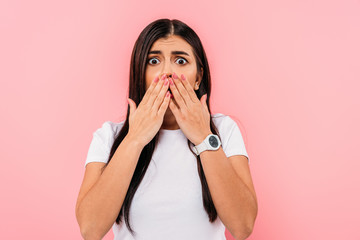 scared pretty brunette girl covering mouth with hands isolated on pink - obrazy, fototapety, plakaty