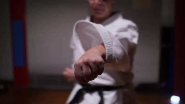 Dramatic slow motion shot of a boy practicing karate punch martial arts at the camera.