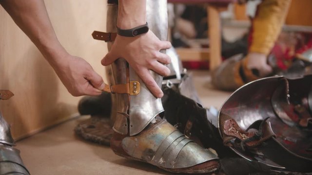 A man putting on an armour for the knights battle training - put on a protection on the calves