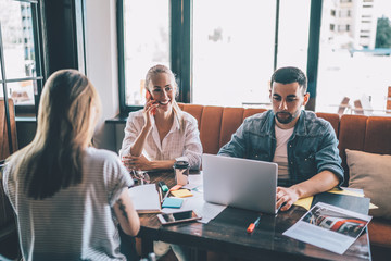 Smiling coworkers sitting at table with laptop