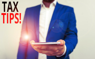 Word writing text Tax Tips. Business photo showcasing compulsory contribution to state revenue levied by government Business concept with man holding mobile phone with touch screen
