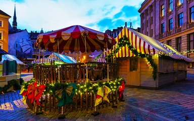 Obraz premium Tree at Night Christmas Market on Dome square in Winter Riga, Latvia. Advent Fair Decoration and Stalls with Crafts Items on the Bazaar. Latvian street Xmas and holiday