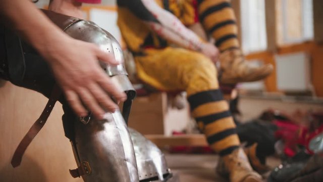 A man putting on an armour on the knee for the knights battle training