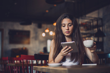 Business woman using tablet and drinking coffee in a cafe.