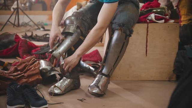 A man putting on an armour on his legs for the knights battle training