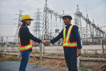 Man and Women Engineering standing shake hand finished project at power plant  electrical system background