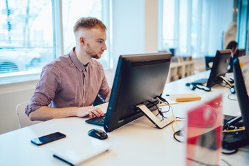 Concentrated man surfing computer at workspace