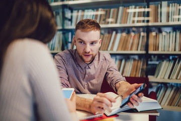 Coworkers speaking and using smartphones in library