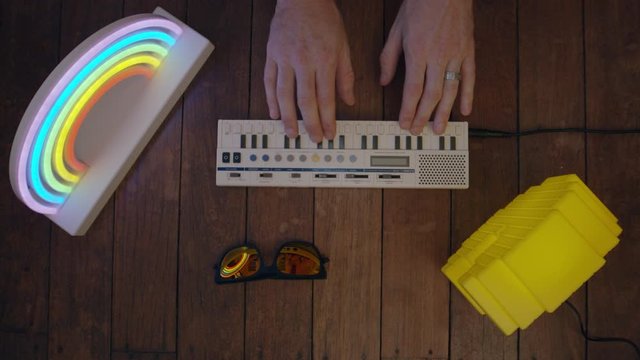 Top down view of hands playing a retro keyboard