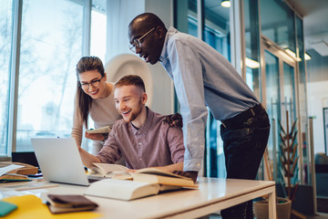 Optimistic mates watching laptop in contemporary building