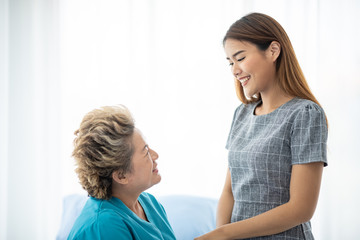 Fototapeta premium Asian daughter or care assistant helping support senior woman or mother