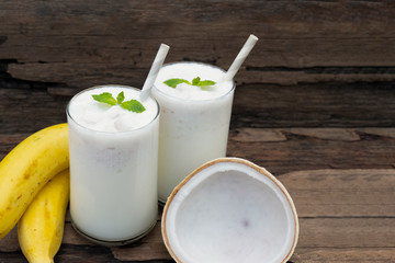 Coconut blend banana milk smoothie drink fresh cocktail shake milkshake vanilla juice fruit beverage food healthy the taste yummy In glass on wooden background.