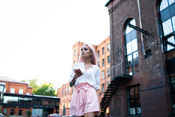 Charming hipster female walking on street with smartphone