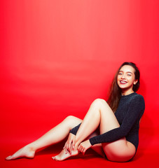 young pretty lady in shiny bodysuit posing on red background, lifestyle people concept