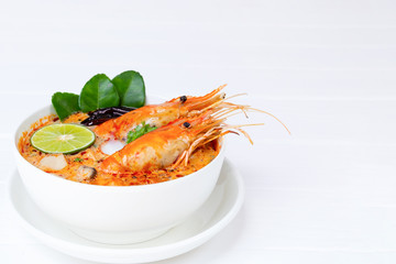 Tom Yum Goong or Shrimp soup spicy sour Soup Traditional food in Thailand contains chili, lime, ginger, galangal, lemongrass, lime leaf,  white wood background.