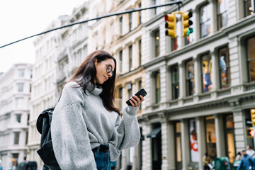 Fototapeta premium Woman standing on sidewalk and browsing mobile phone