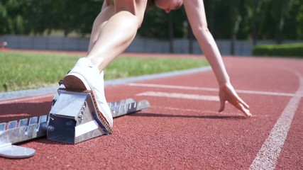 City stadium. Young girl athlete start running from block. Slow motion, back view