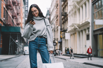 Obraz premium Cheerful young woman surfing on smartphone on street