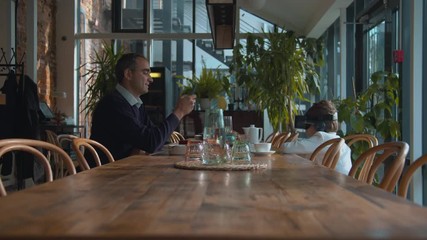 Boy sits in virtual reality glasses, man is on his phone - Powered by Adobe