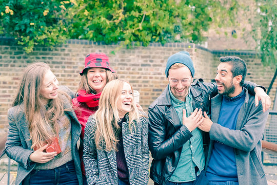Group of happy young friends having fun on city street. Group of millennial people walking through city park together. Travel and friendship concept - Image