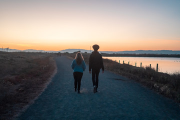 Young Woman and Man Walking at Wetlands During Sunset