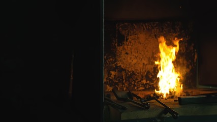 Forge fire in furnace. Blacksmith tempers a steel product in a stove. Smithy forging for hardening and heating iron. Blacksmith makes iron for manufacture of fireplace, stove. Burner Slow Motion.