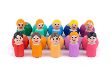 A close-up of a children's toy made of natural wood in the form of little people of different colors with a smile is standing in an even row on a white isolated background. 
