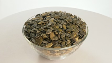 Nuts peeled pumpkin seed rotate are on a table in a plate. Snack in transparent dish on an isolated...
