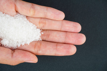 Top view of sugar on hand over black background. Health and care concept