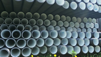Warehouse of finished plastic pipes industrial outdoors storage site. Manufacture of plastic water pipes factory. Process of making plastic tubes on the machine tool with the use of water and air